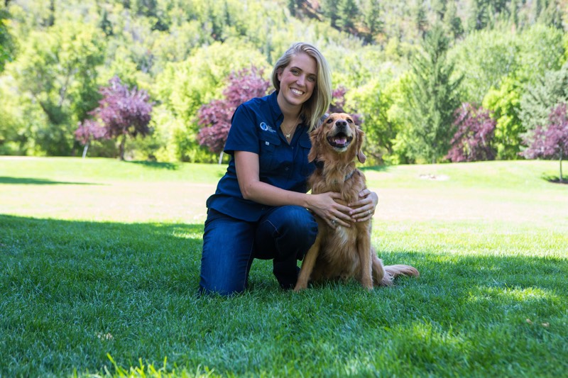 Dog Training Elite Owner poses with her dog in the grass.