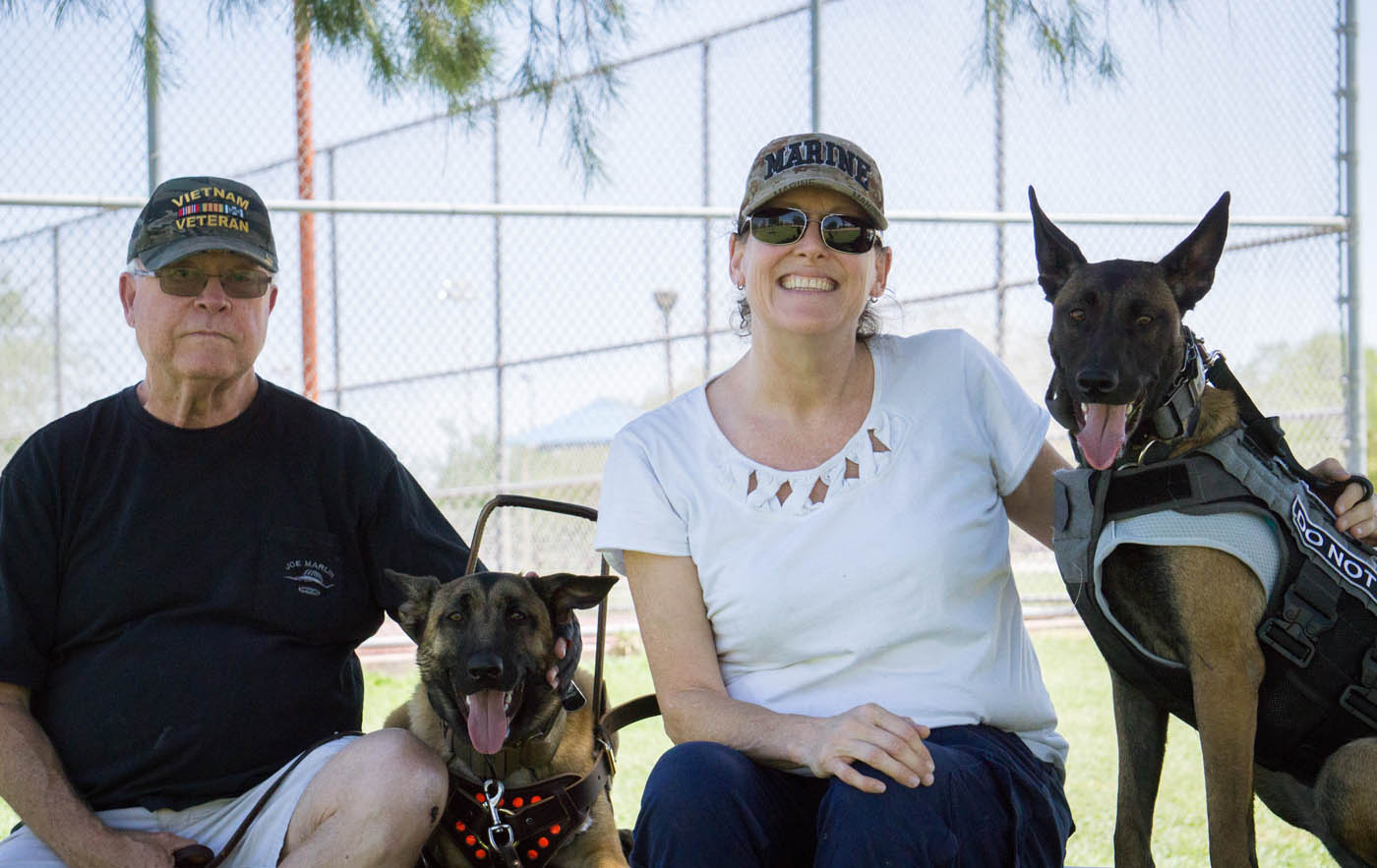 Two PTSD service dogs trained by the experts at Dog Training Elite sitting with their owners.